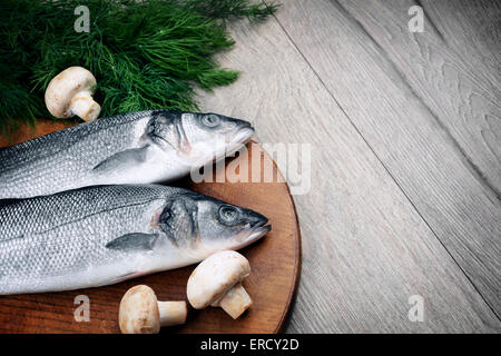 Le Bar Cru poisson sur la planche en bois avec des légumes Banque D'Images