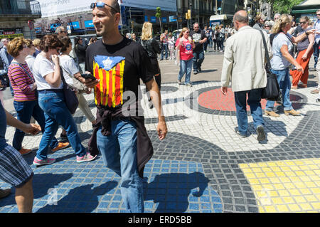 Homme avec un pro-indépendance senyera drapeau estelada T-shirt marcher sur le pavé mosaïque par Joan Miró sur la Rambla, Barcelone, Espagne Banque D'Images