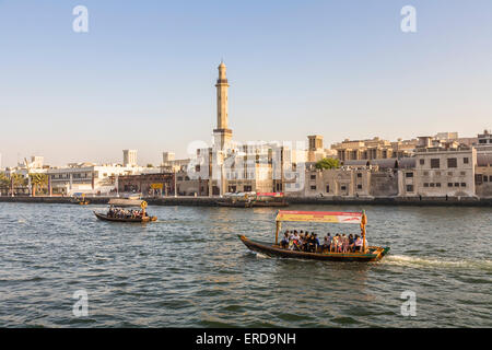 Vue sur le fleuve d'un ferry local traditionnel traversant Dubai Creek, de Bur Dubai à Deira, Dubaï, Émirats arabes Unis, minaret de la Grande Mosquée en arrière-plan Banque D'Images