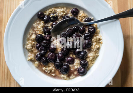 Des bleuets frais et d'avoine dans un bol blanc avec une cuillère à soupe Banque D'Images