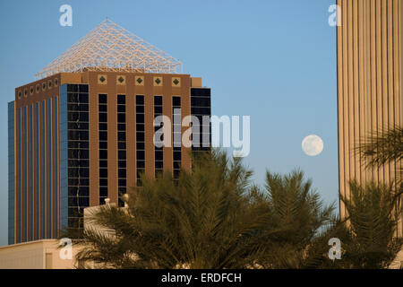 Pleine lune passant entre les bâtiments plus de palmiers à Phoenix Banque D'Images