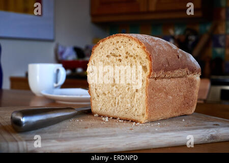 Couper un morceau de pain sur une carte de pain dans une cuisine maison Banque D'Images