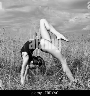 Caucasian woman faisant backbend in tall grass Banque D'Images