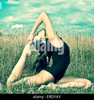 Caucasian woman faisant backbend in tall grass Banque D'Images