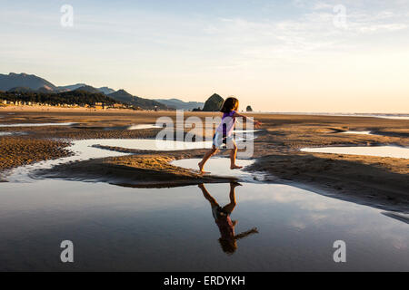 Caucasian girl tournant dans les mares d'eau sur la plage, Cannon Beach, Oregon, United States