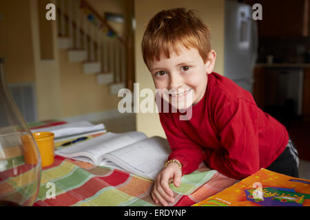 Caucasian boy doing homework at table Banque D'Images