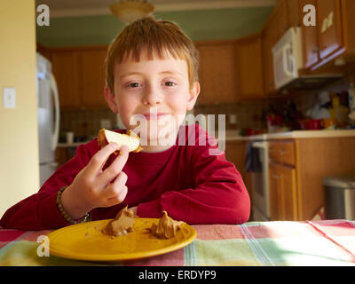 Caucasian boy eating apple avec le beurre d'arachide snack Banque D'Images