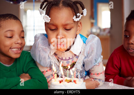 Gâteau Black girl blowing out candles at party Banque D'Images