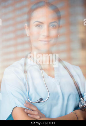 Caucasian doctor standing with arms crossed at window Banque D'Images