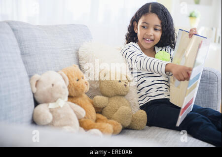 Mixed Race girl enseignement nounours sur canapé Banque D'Images