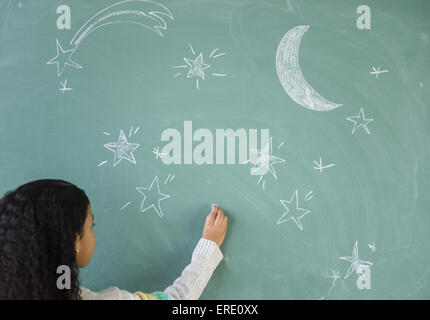 Mixed Race student dimensions stars on chalkboard in classroom Banque D'Images