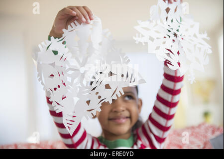 Mixed Race girl holding paper snowflakes Banque D'Images