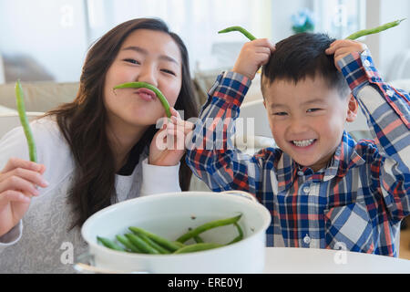 Frère et soeur asiatique jouant avec des légumes Banque D'Images