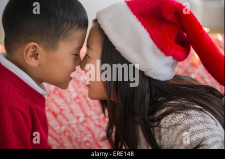 Frère et soeur asiatique rubbing noses at Christmas Banque D'Images