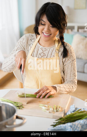 Pacific Islander woman slicing vegetables in kitchen Banque D'Images