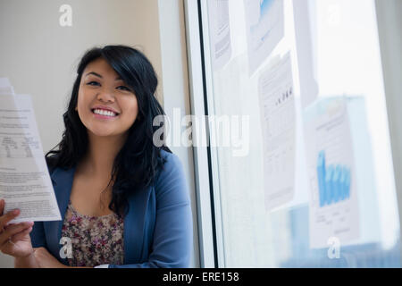 Pacific Islander woman reading paperwork près de window Banque D'Images