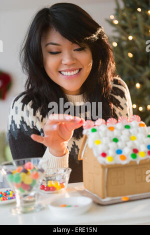 Pacific Islander woman decorating gingerbread house Banque D'Images