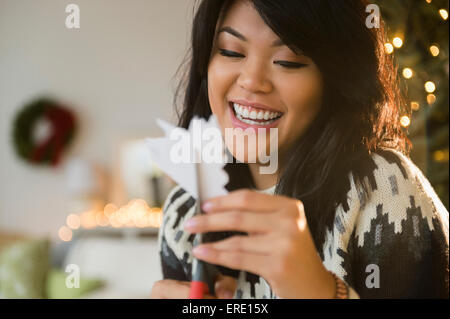 Pacific Islander woman cutting paper snowflakes Banque D'Images