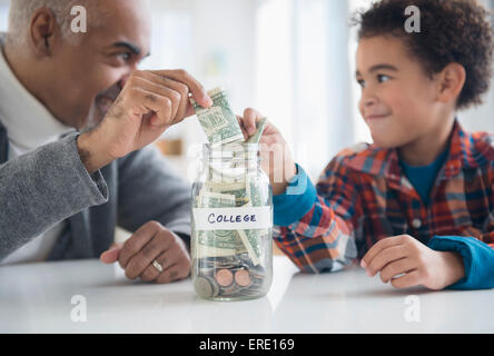Mixed Race grand-père et petit-fils d'économiser de l'argent dans la région de college fund jar Banque D'Images
