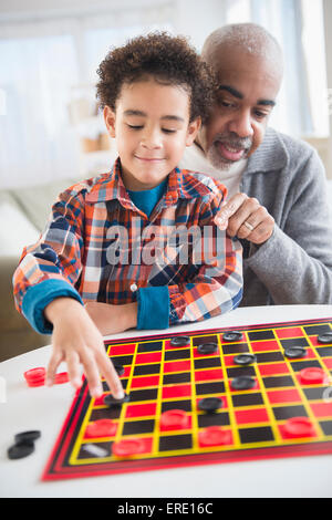 Mixed Race grand-père et petit-fils jouer aux dames Banque D'Images