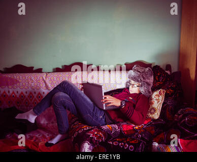 Mixed Race boy wearing fur hat sitting on sofa Banque D'Images