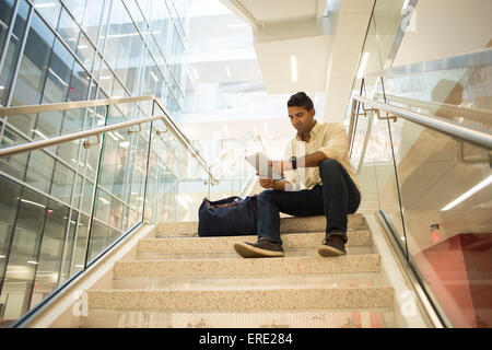 Asian businessman using digital tablet on office staircase Banque D'Images