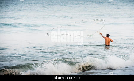 Man throwing filet de pêche dans les vagues de l'océan Banque D'Images