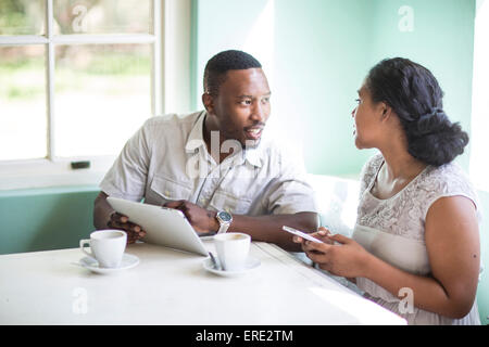 Couple using cell phone et digital tablet at breakfast table Banque D'Images