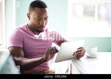 Black man using digital tablet au petit déjeuner Banque D'Images