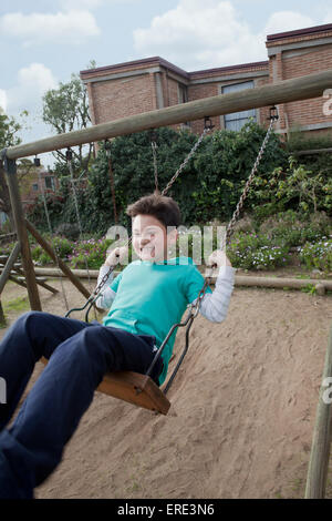 Hispanic boy playing on swing in backyard Banque D'Images