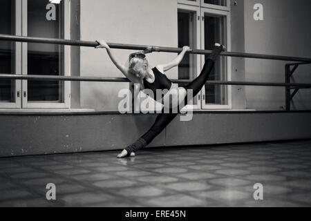 Caucasian dancer faire fentes sur barre en studio Banque D'Images