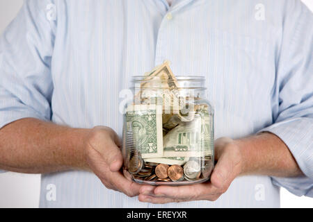 Man holding sa retraite retraite tirelire argent compte dans ses mains dans un bocal en verre. Banque D'Images