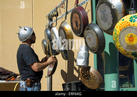 Homme jouant de la percussion d'écoute composée de poêles à frire dans le cadre d'une exécution par un groupe composé d'instruments Banque D'Images