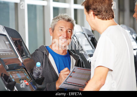 Formateur dans un centre de remise en forme de conseiller senior sur un tapis roulant Banque D'Images