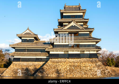 Une attraction touristique populaire, le donjon du château de Matsumoto au Japon dans l'heure d'or de l'après-midi juste avant le coucher du soleil avec un fond bleu ciel. Banque D'Images