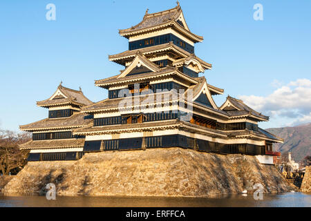 Une attraction touristique populaire, le donjon du château de Matsumoto au Japon dans l'heure d'or de l'après-midi juste avant le coucher du soleil avec un fond bleu ciel. Banque D'Images