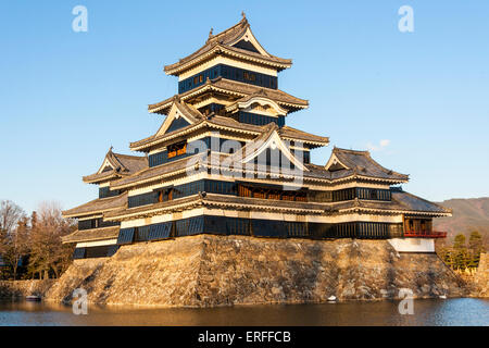 Une attraction touristique populaire, le donjon du château de Matsumoto au Japon dans l'heure d'or de l'après-midi juste avant le coucher du soleil avec un fond bleu ciel. Banque D'Images