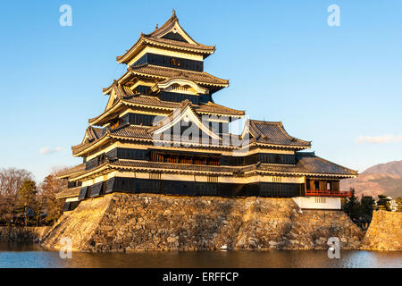 Une attraction touristique populaire, le donjon du château de Matsumoto au Japon dans l'heure d'or de l'après-midi juste avant le coucher du soleil avec un fond bleu ciel. Banque D'Images