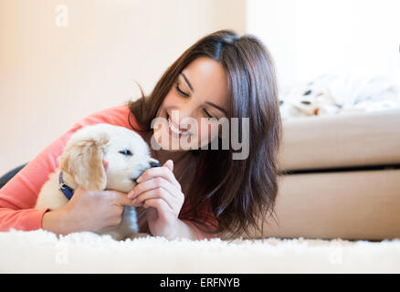 Woman lying on floor avec un chiot Banque D'Images