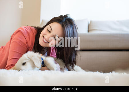 Woman lying on floor avec un chiot Banque D'Images