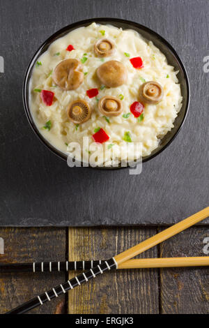 Lait de riz aux Champignons Safran Cap sur un bol sur une plaque en ardoise sur un fond de bois avec des baguettes Banque D'Images