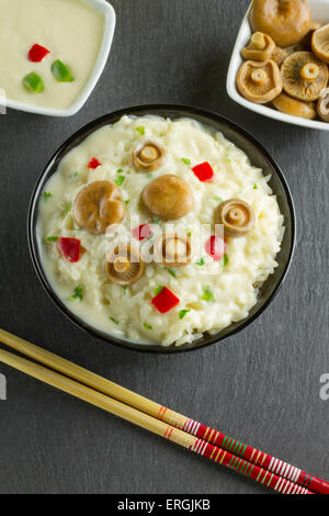 Lait de riz aux Champignons Safran Cap sur un bol sur une plaque en ardoise, avec champignons, sauce et baguettes Banque D'Images