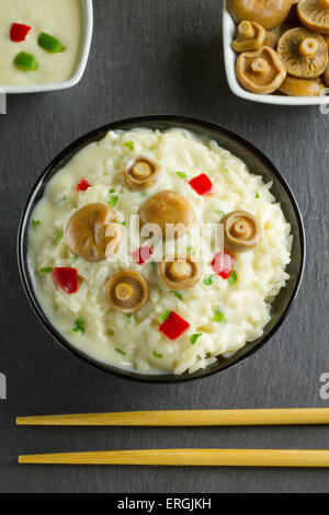 Lait de riz aux Champignons Safran Cap sur un bol sur une plaque en ardoise, avec champignons, sauce et baguettes Banque D'Images