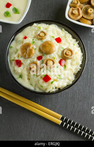 Lait de riz aux Champignons Safran Cap sur un bol sur une plaque en ardoise, avec champignons, sauce et baguettes Banque D'Images