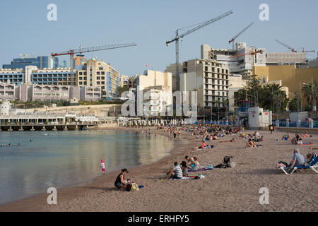 Les touristes et les habitants profiter du soleil en fin d'après-midi sur la plage à St Georges Bay. La construction se poursuit en arrière-plan Banque D'Images