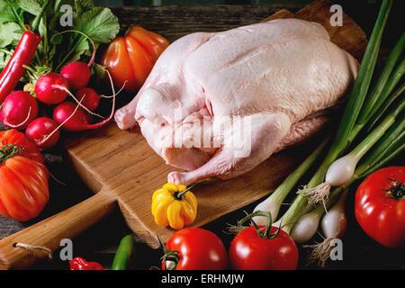 Matières jeune canard sur planche à découper en bois avec des légumes frais mûrs sur table en bois. Atmosphère rustique foncé. Banque D'Images