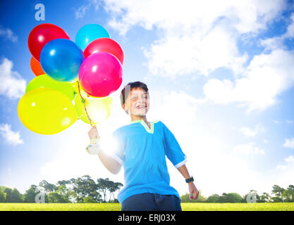Happy boy en plein air avec une douzaine de ballons à l'hélium. Banque D'Images