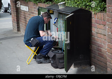 Ingénieur BT sur une boîte de jonction sur la route England UK Banque D'Images