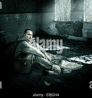 L'homme militaire avec masque à gaz assise sur un étage de ruines de bâtiments de monde post-apocalyptique Banque D'Images