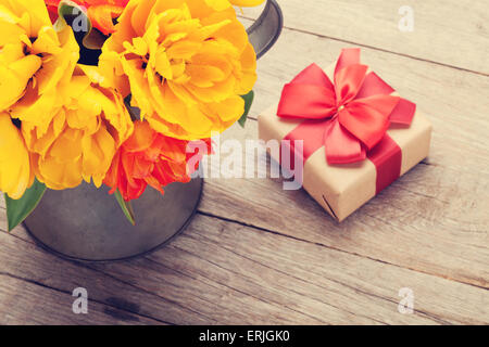 Bouquet de tulipes colorées et boîte-cadeau sur table en bois. Tons rétro Banque D'Images